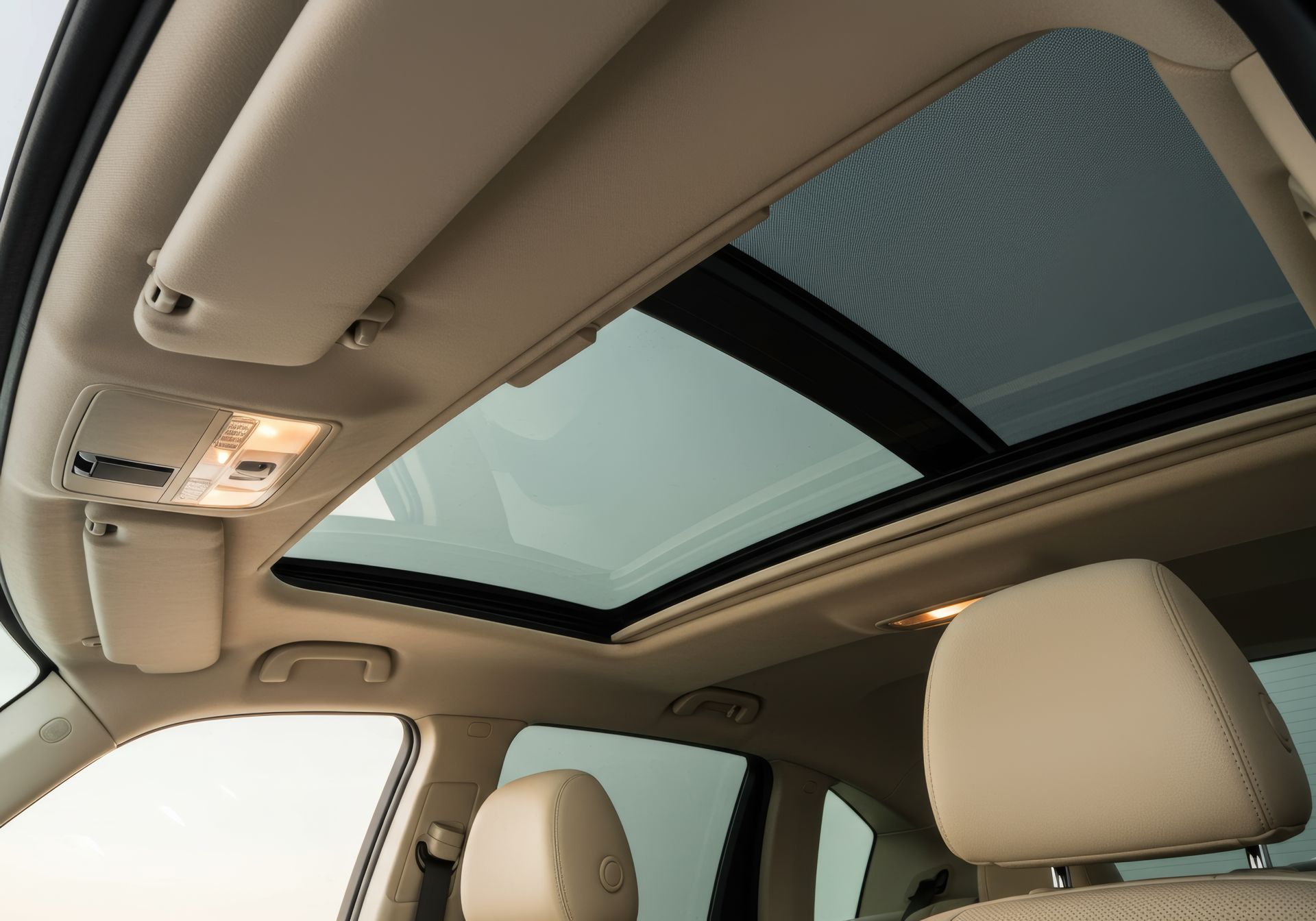 Intérieur de voiture avec toit ouvrant, sièges beiges, éclairage intérieur.