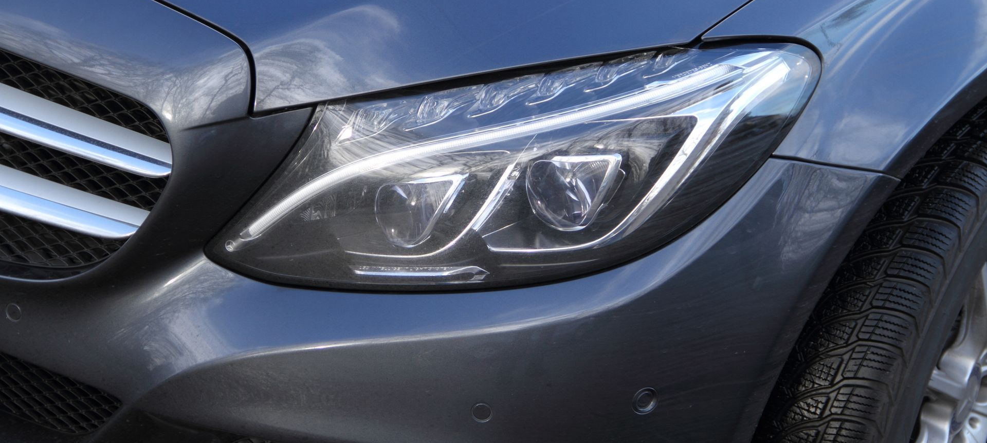 Gros plan sur un phare gris Mercedes-Benz, montrant les détails du bloc optique.