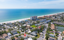 Aerial view of a coastal city with beach, ocean, and buildings along the shoreline.