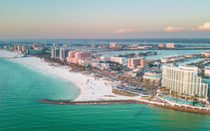 Aerial view of a white sandy beach, turquoise water, and beachfront hotels at sunset