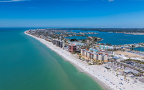 Aerial view of a sandy beach and turquoise bay beside a dense coastal town.