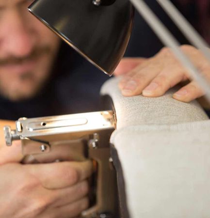 Un hombre está usando una máquina de coser para coser un trozo de tela.