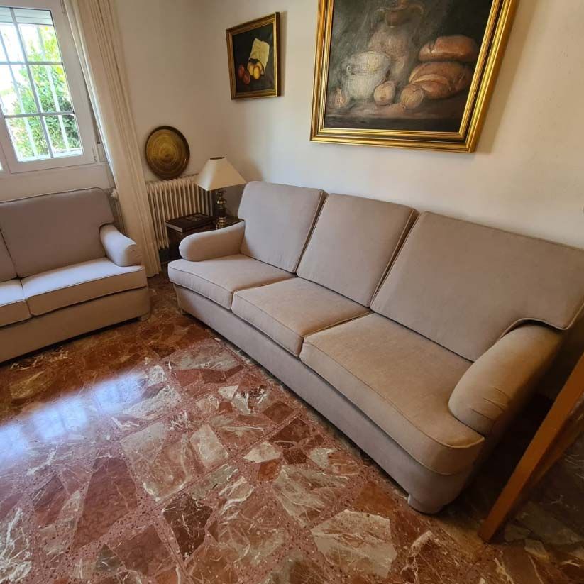 Una sala de estar con un sofá, una silla y un cuadro en la pared.