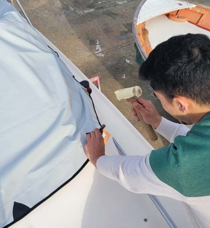 Un hombre está trabajando en un barco con un martillo.