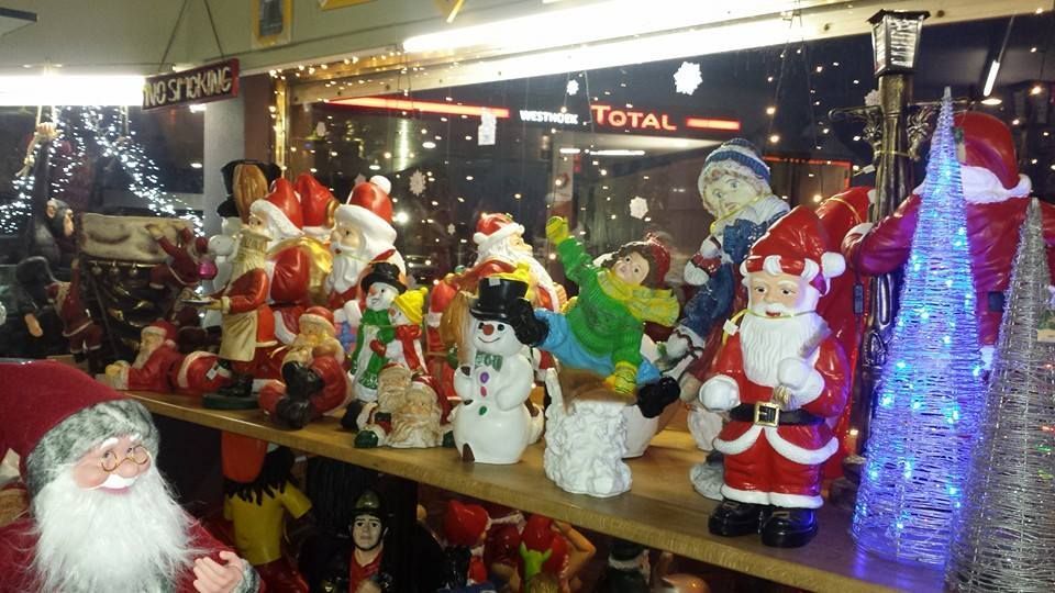 Kerstdecoratie met kerstmanbeeldjes, sneeuwpoppen en blauwe lichtjes op een plank.