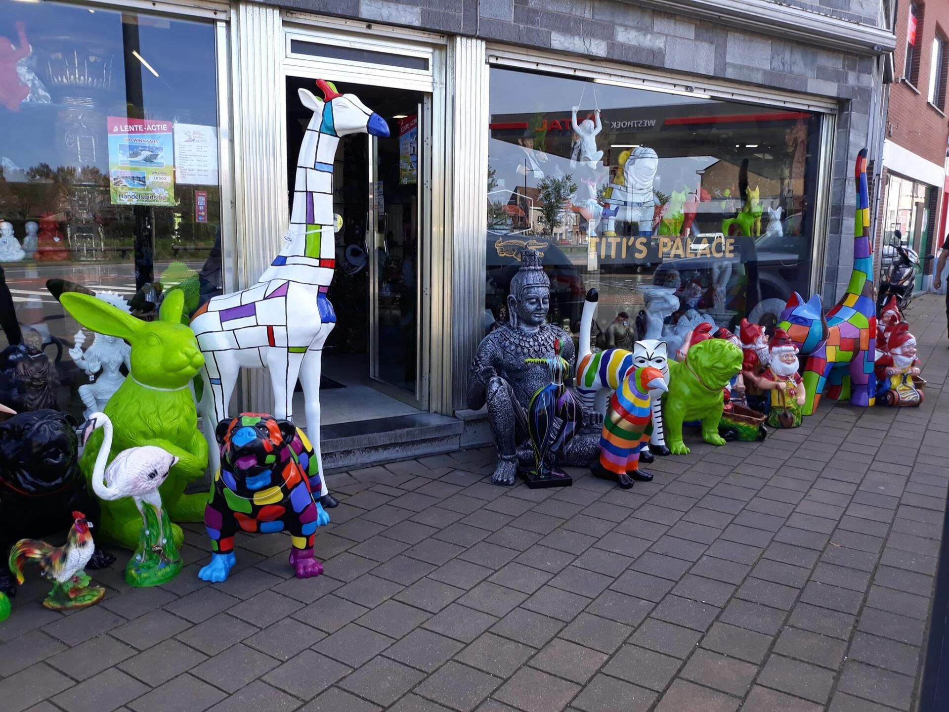 Winkeletalage met kleurrijke dierensculpturen en mannequins buiten een winkel