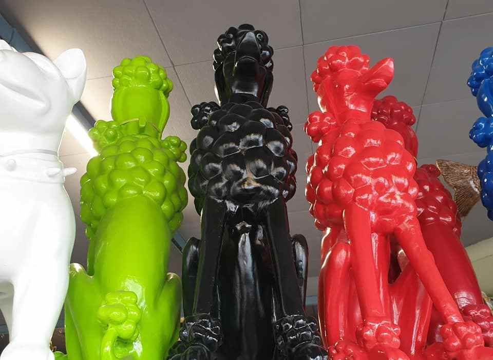 Kleurrijke, glanzende dinosaurusbeeldjes staan op een plank opgesteld, waaronder witte, groene, zwarte, rode en blauwe exemplaren.