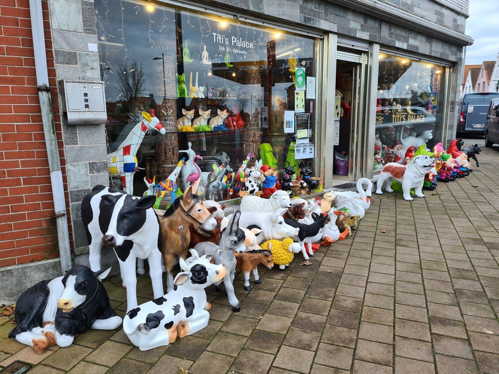 Een etalage met pluche koeienkoeien staat opgesteld op de stoep voor een winkel.