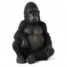 Een zwarte gorillafiguur die rechtop zit op een witte achtergrond.