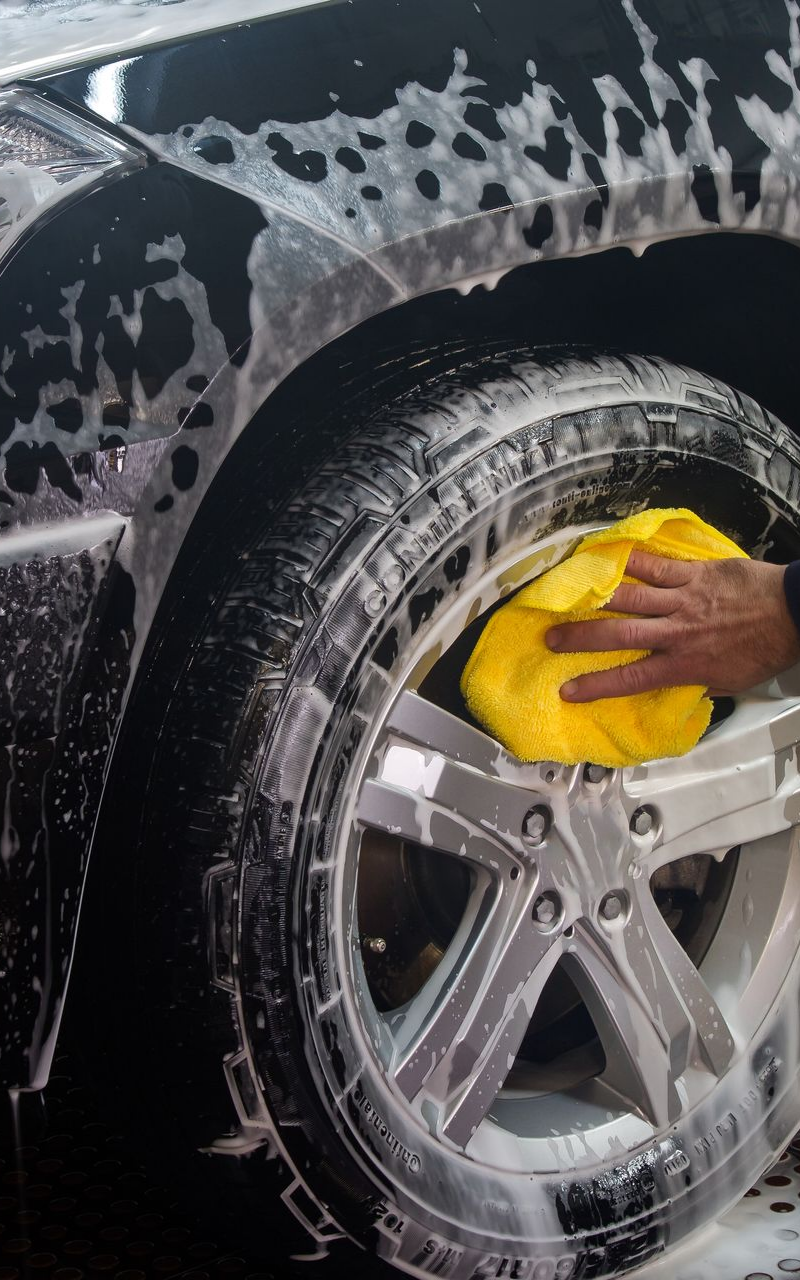 Vers la page Nettoyage pour les professionnels. Le nettoyage d'une roue avec un chiffon jaune.