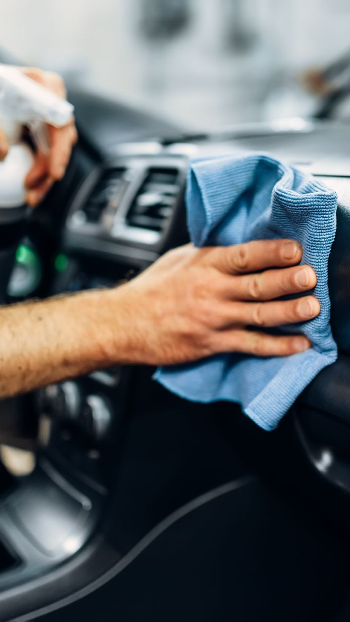 Vers la page Nettoyage complet intérieur. Le nettoyage d'un tableau de bord avec un chiffon.