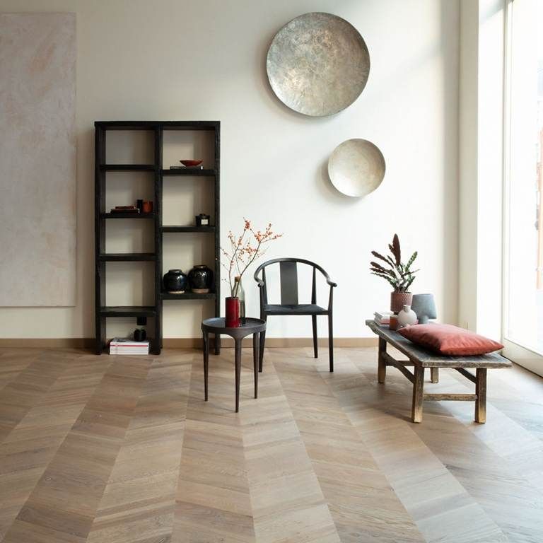 Minimalistisches Wohnzimmer mit Fischgrätparkett, schwarzem Sessel und Regal, Bank und Wanddekoration