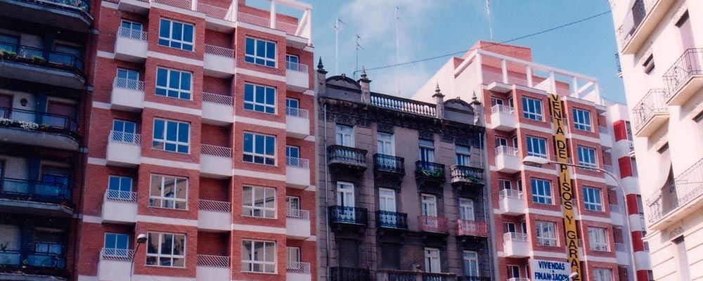 Una hilera de edificios con balcones y un cielo azul al fondo.