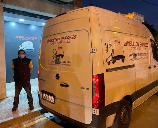 Un hombre que lleva una máscara está de pie junto a una camioneta blanca.