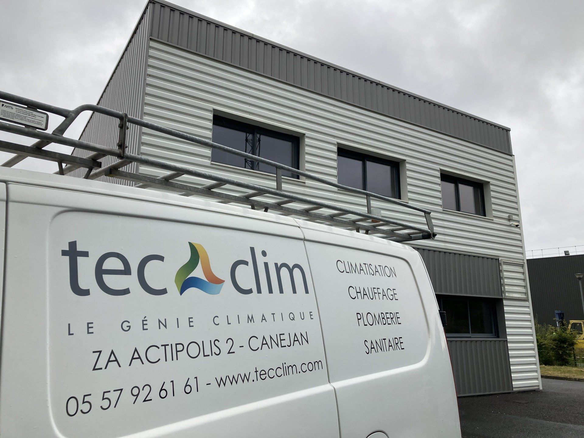 Panneau Tecclim sur une camionnette blanche devant un bâtiment industriel gris.