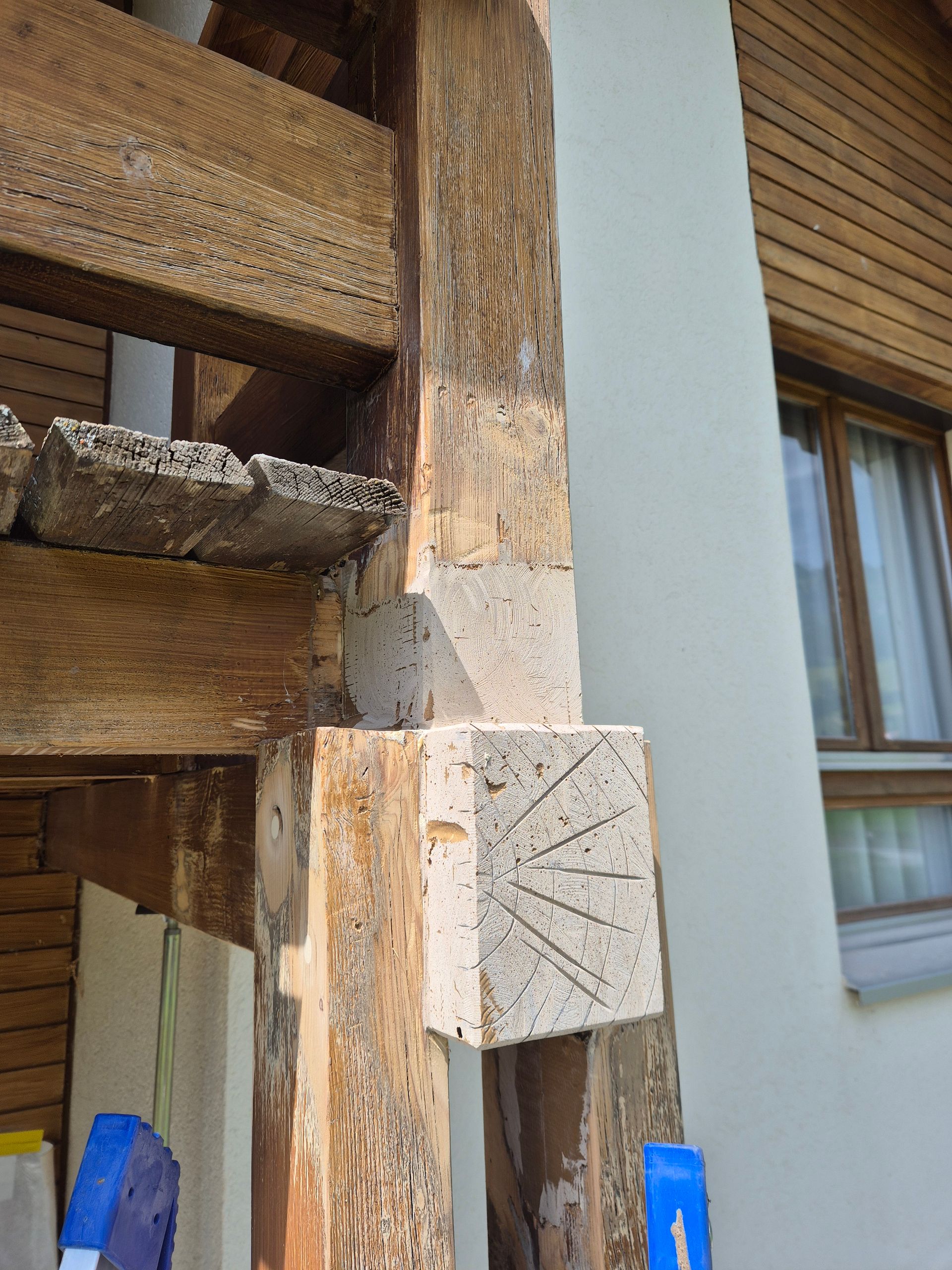 Structure de maison en bois avec poutres patinées et un bloc de béton.