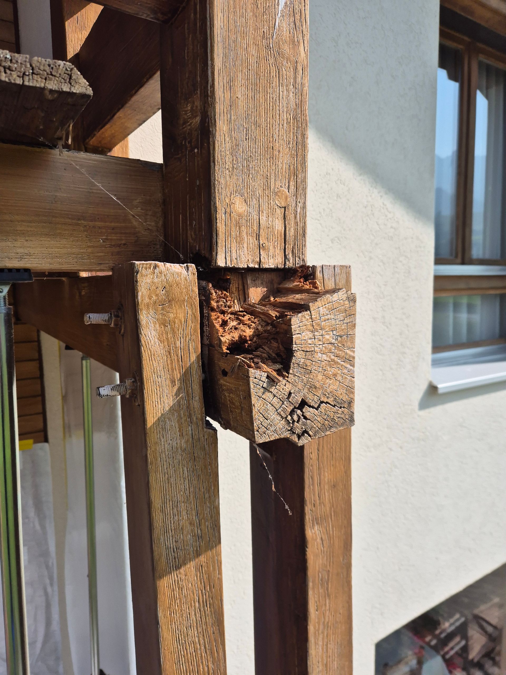 Poteau en bois présentant des dommages importants dus à la pourriture dans un environnement extérieur altéré.
