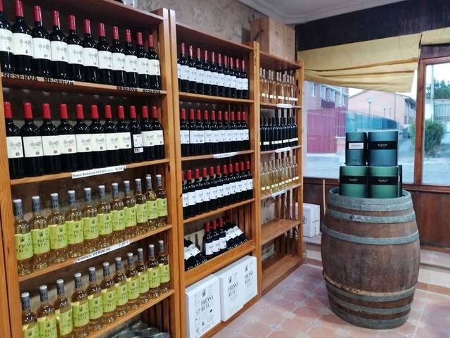 Estantes llenos de botellas de vino y un barril de madera.