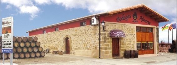 Un gran edificio de piedra con barriles delante.
