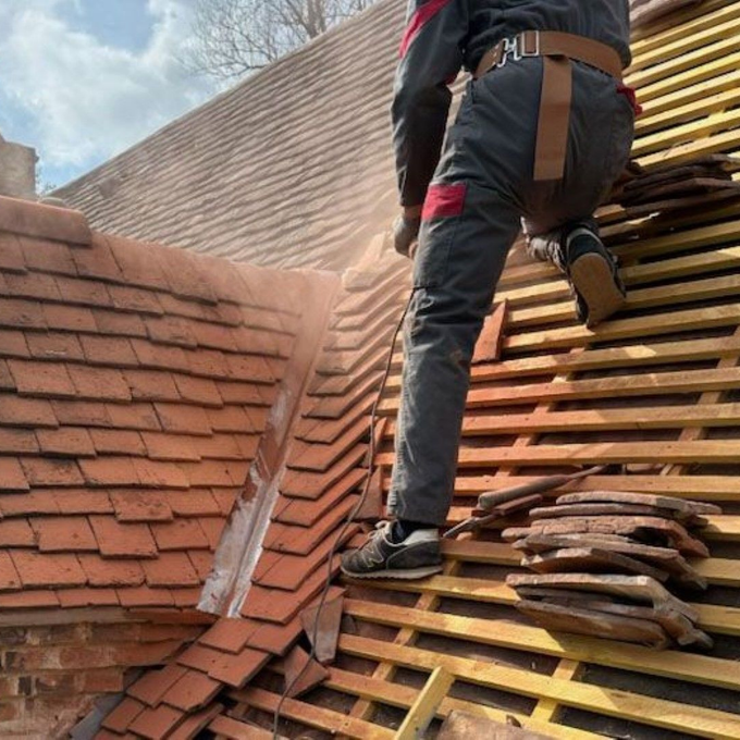 Personne utilisant un marteau pour fixer une tuile en terre cuite
