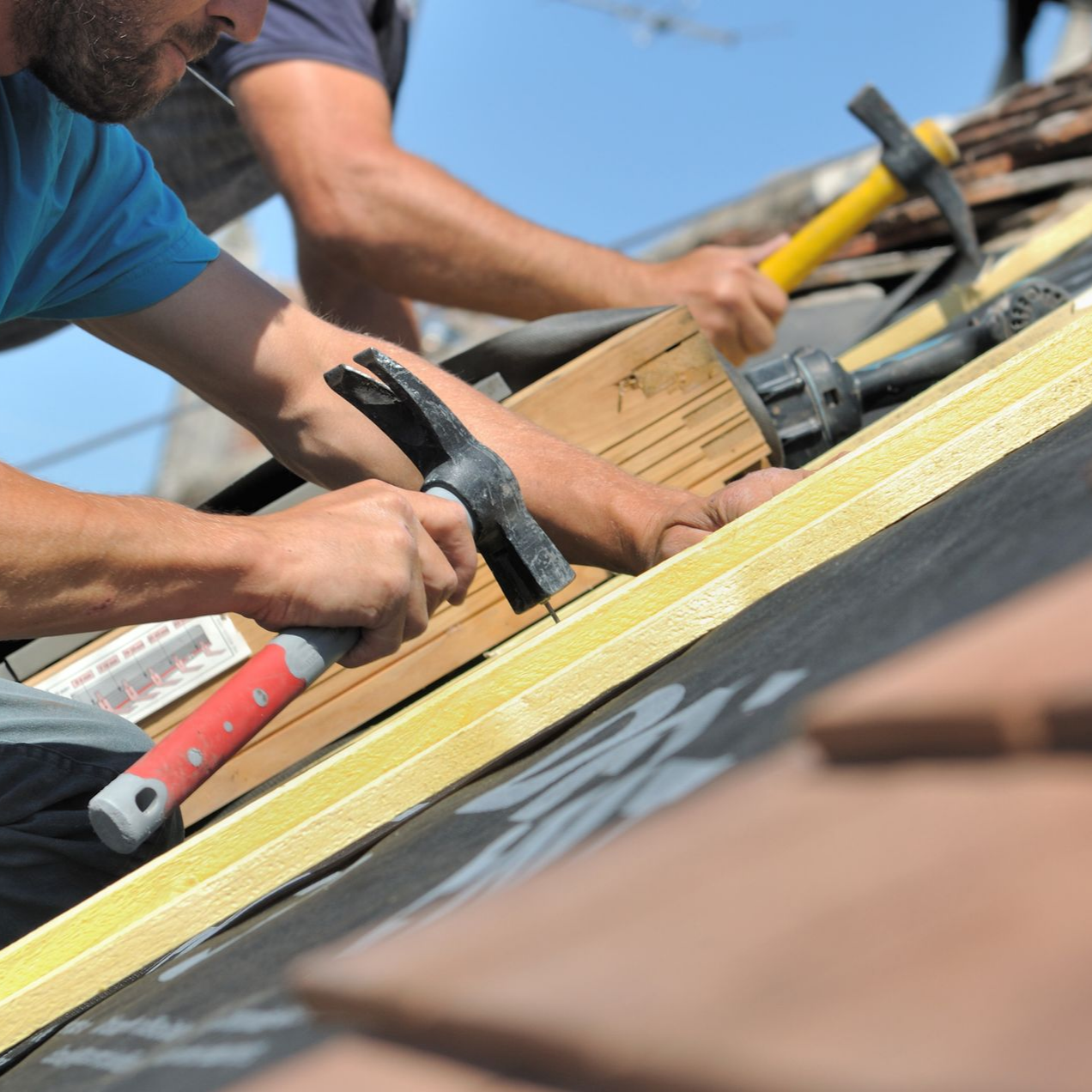 Deux couvreurs martèlent un toit au soleil