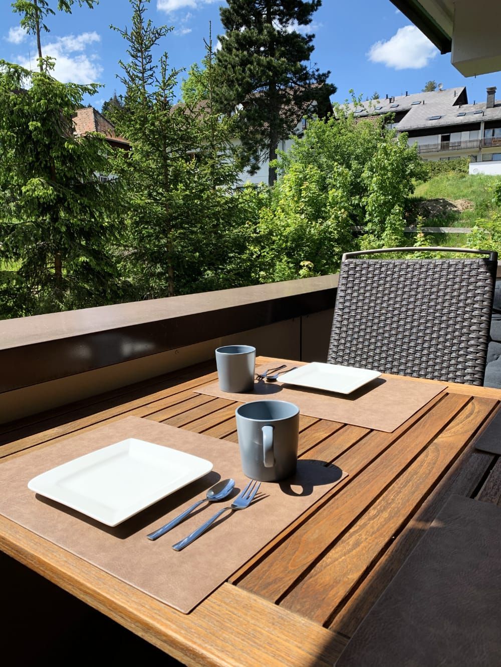 Balkon mit Holztisch und Frühstücksgeschirr mit Blick ins Grüne in der Ferienwohnung in Schönwald im Schwarzwald