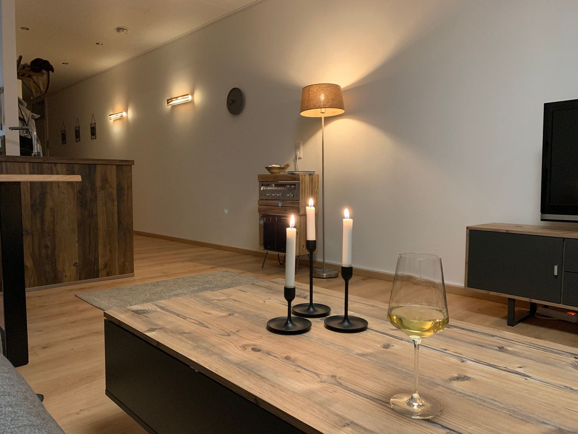 Gemütliches Wohnzimmer mit Kerzen auf dem Couchtisch und offener Küche in der Ferienwohnung in Schönwald im Schwarzwald