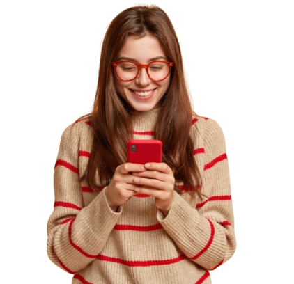 Une femme portant des lunettes rouges et un pull rayé sourit en regardant son téléphone rouge.