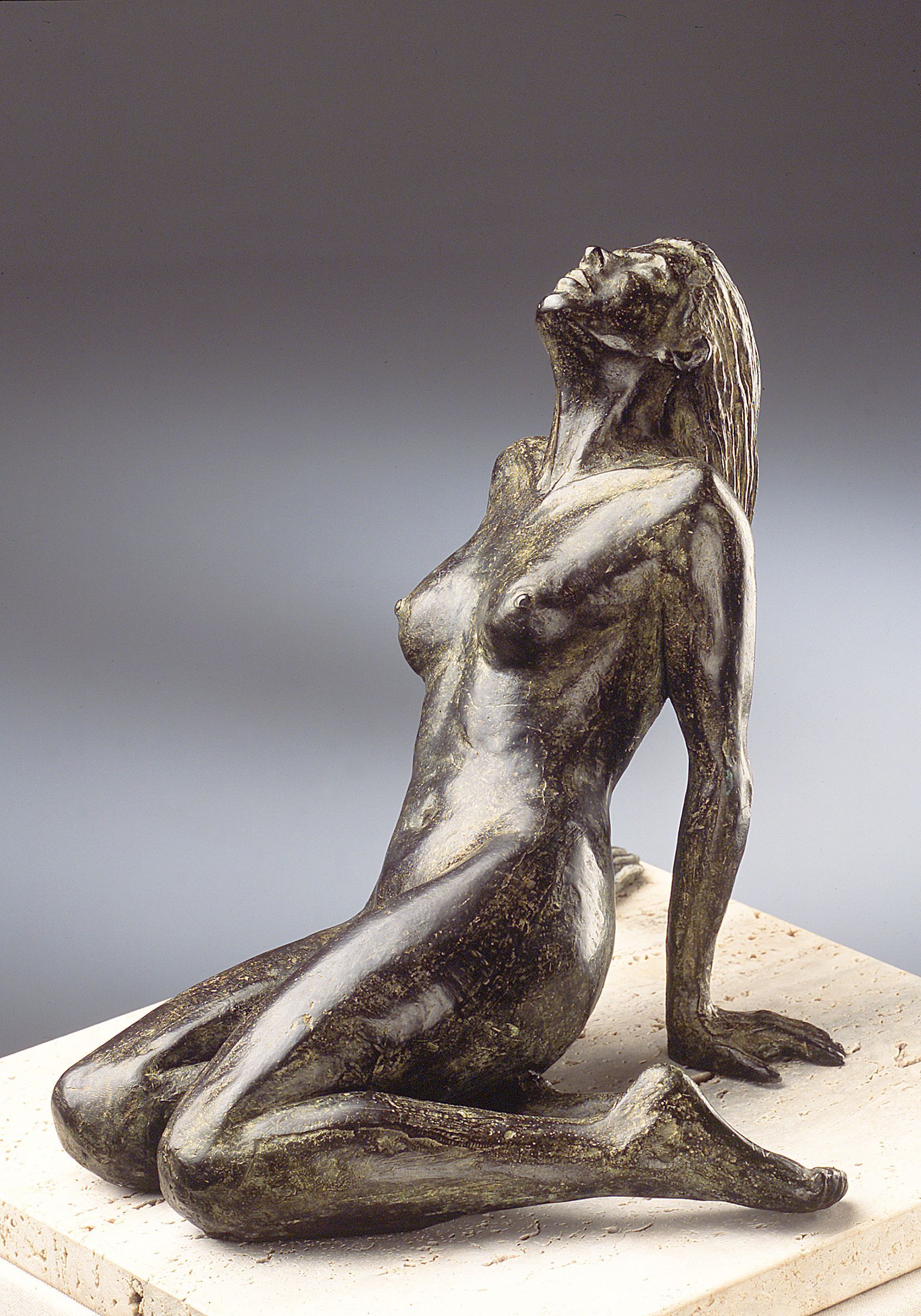 Una estatua de una mujer arrodillada sobre una base de mármol