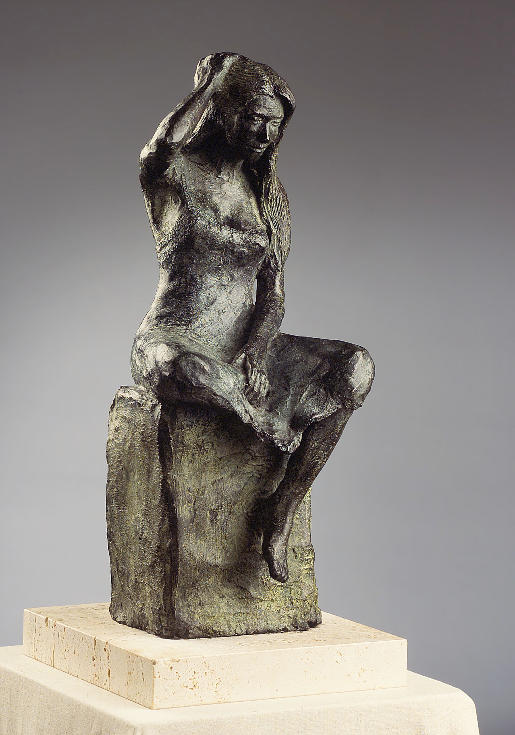 Una estatua de bronce de una mujer sentada en una roca.