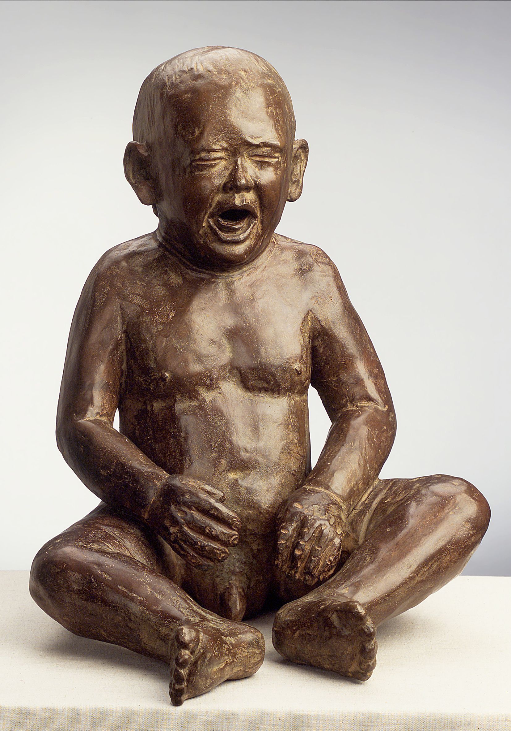 Una estatua de un bebé llorando con la boca abierta