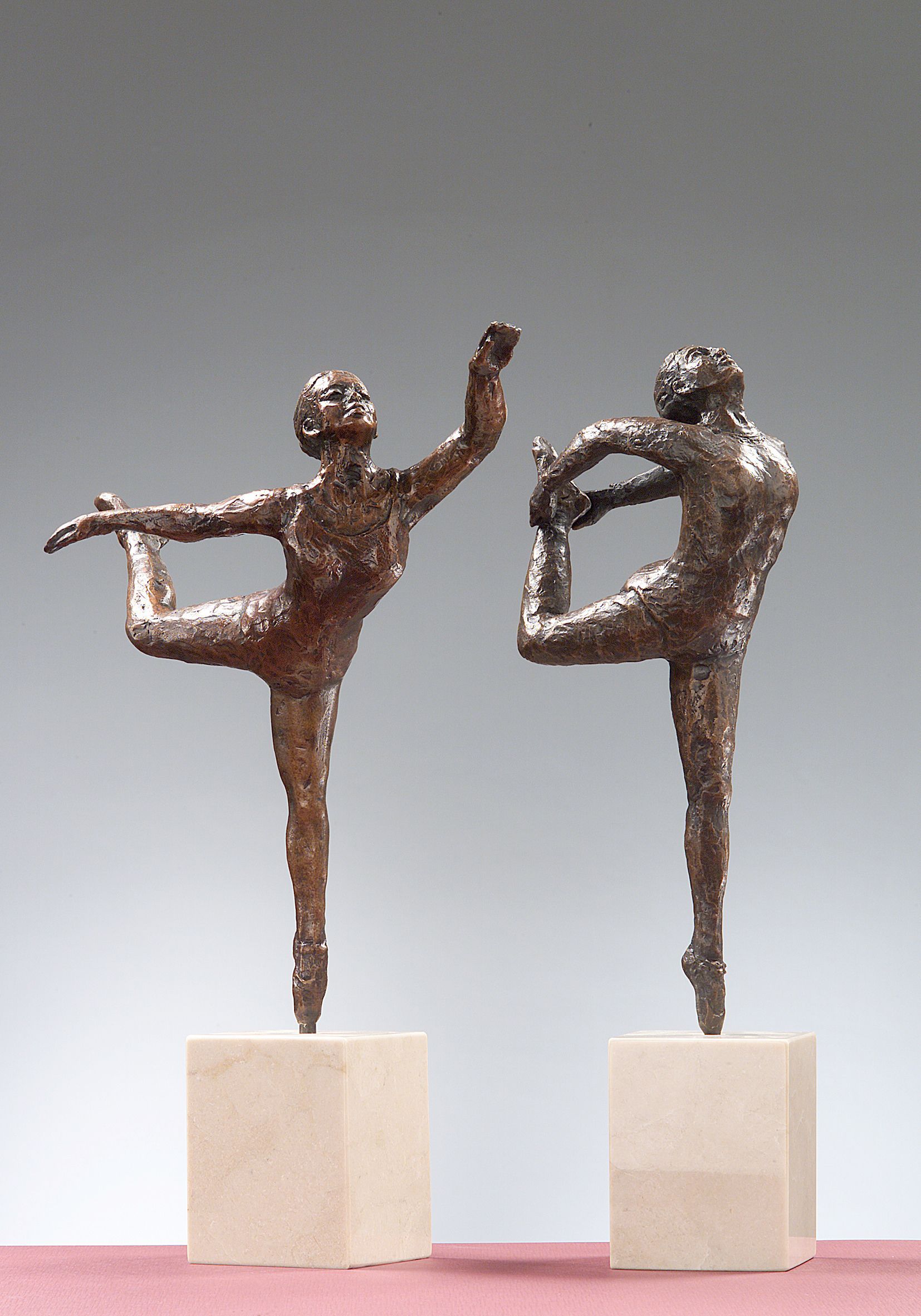 Dos estatuas de bronce de dos personas de pie sobre una pierna.