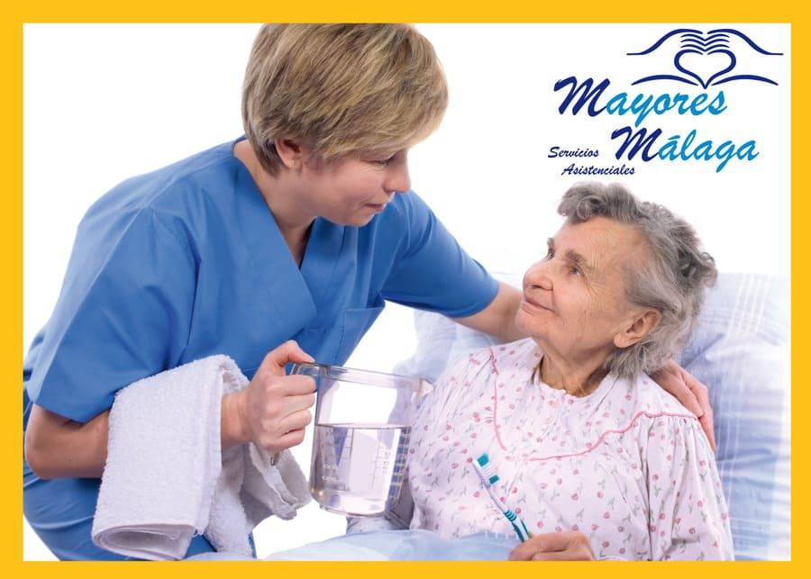 Una enfermera está ayudando a una anciana a cepillarse los dientes.