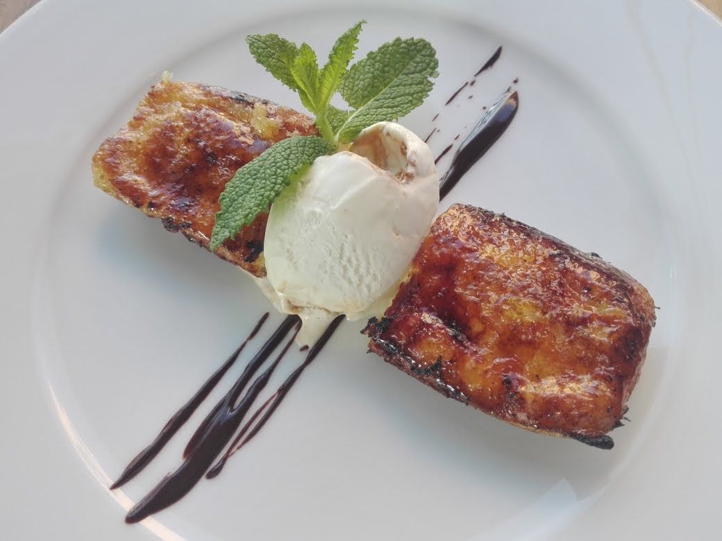 Plato de postre con hojaldre caramelizado, helado de vainilla, sirope de chocolate y guarnición de menta.