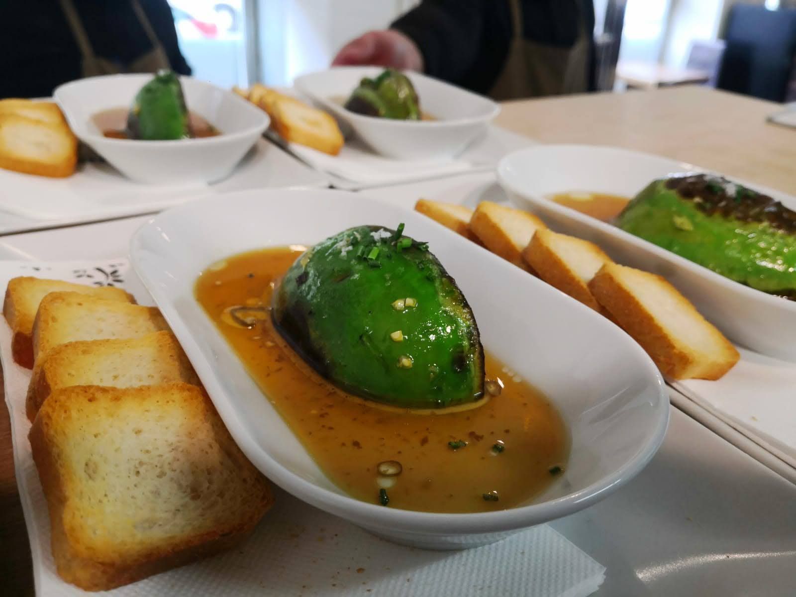 Platos blancos de postre con cobertura verde, salsa de caramelo y tostadas sobre una mesa.