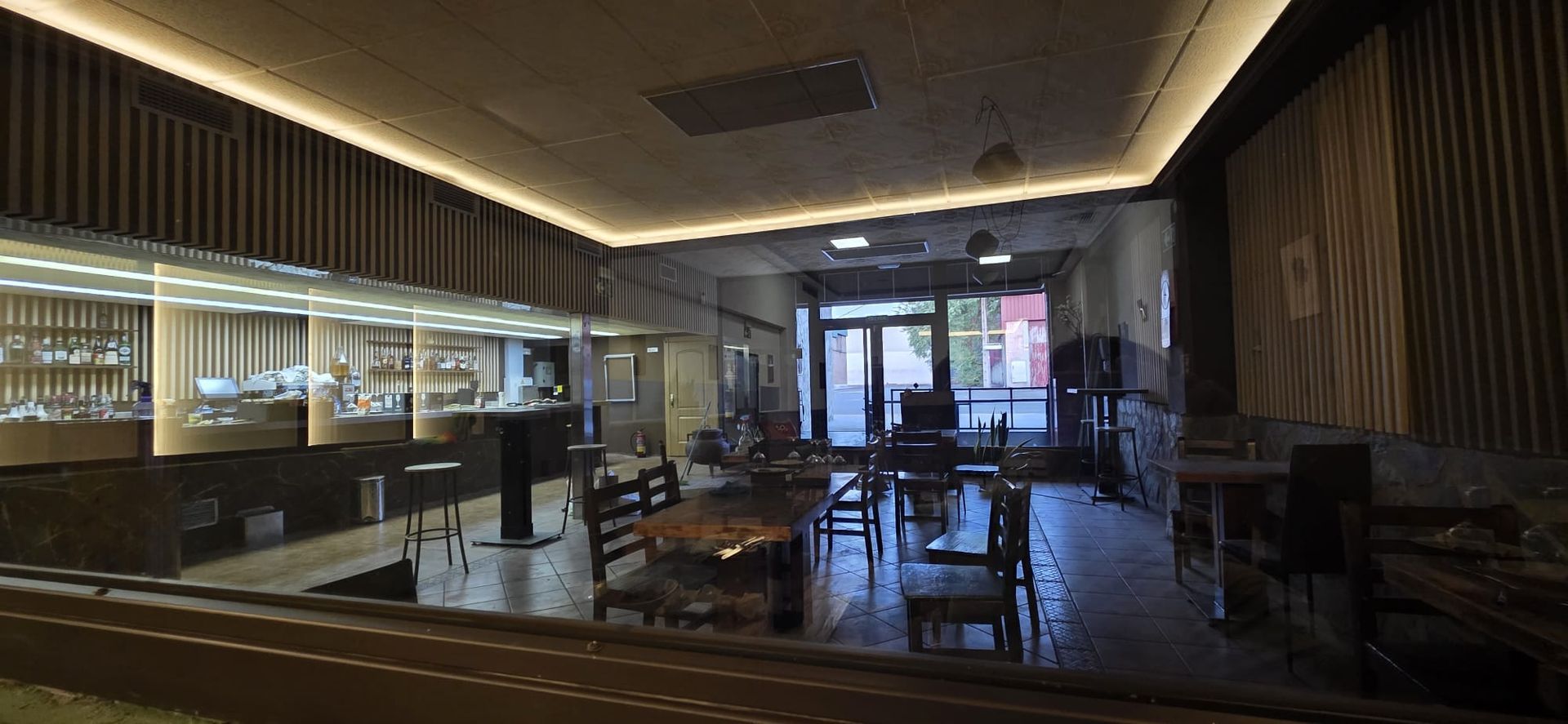 El interior del restaurante, de estilo contemporáneo y con iluminación tenue, cuenta con muebles de madera, iluminación moderna y una larga barra acristalada.