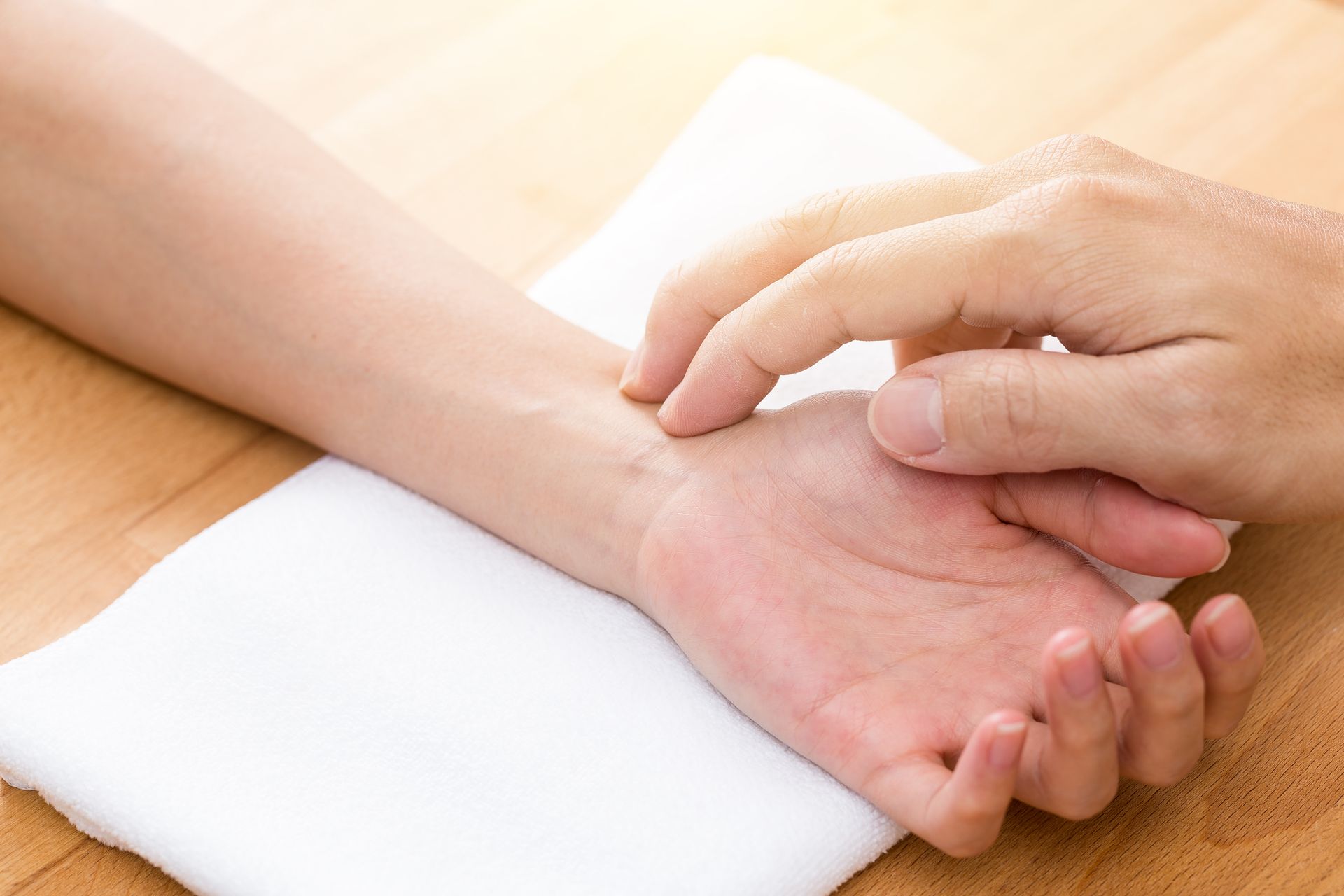 Une personne prend le pouls d'un patient sur une table en bois.