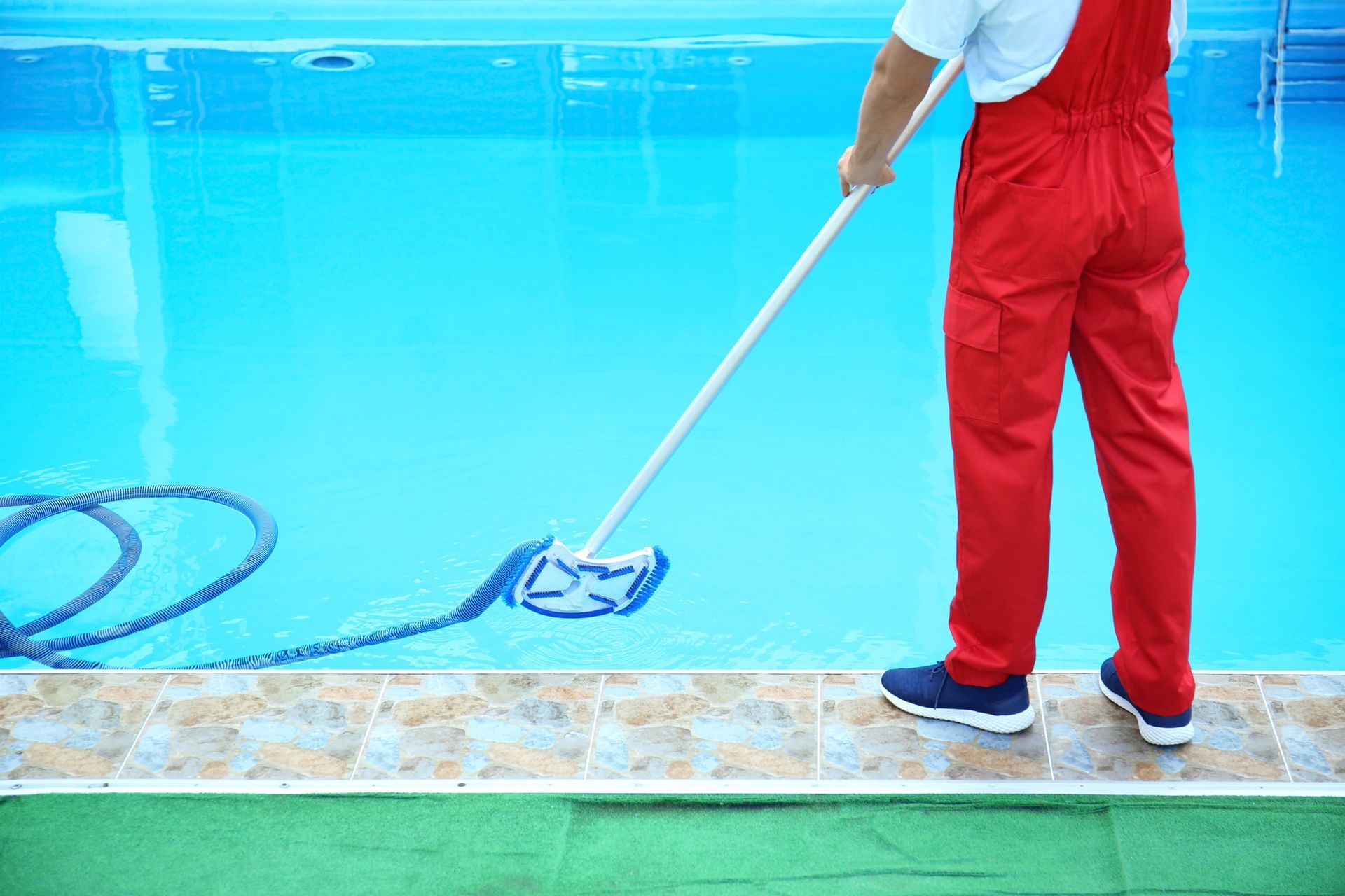 Un hombre está limpiando una piscina con un trapeador.