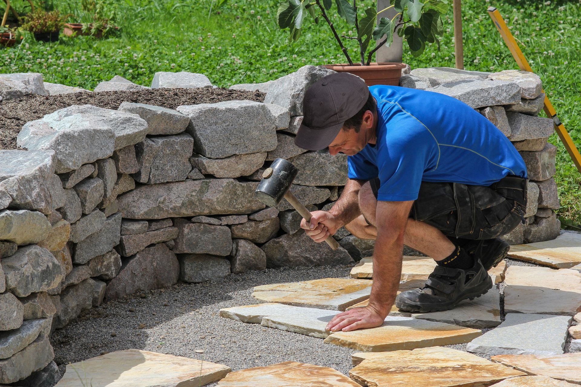 Un hombre está trabajando en un muro de piedra con un martillo.