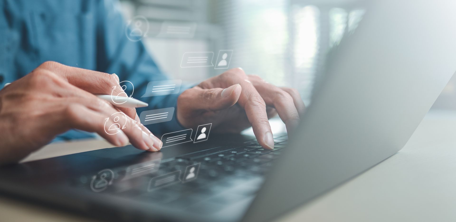 Une personne tape sur un clavier d'ordinateur portable dans un espace de travail lumineux aux tons bleus.