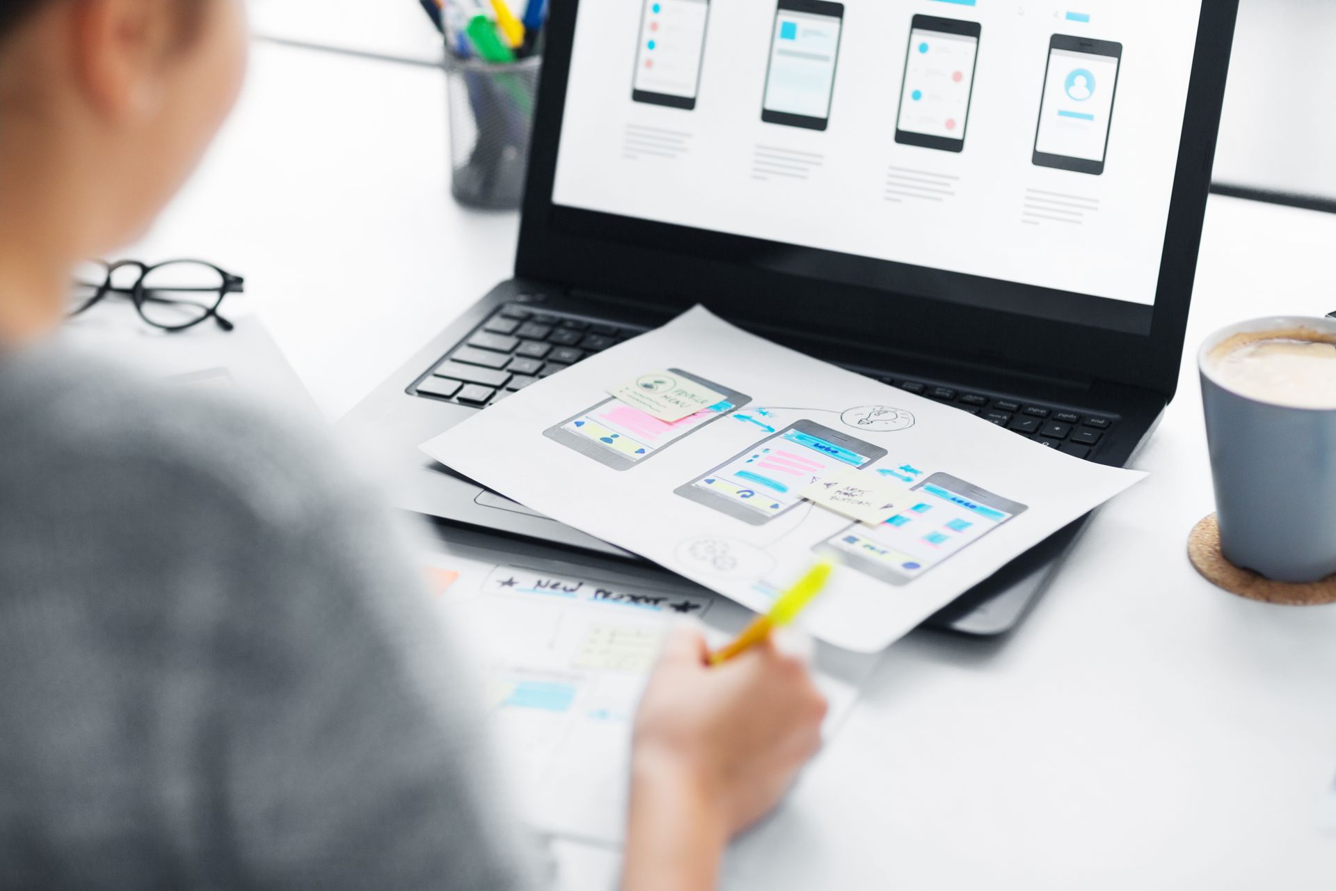 Une personne réalise des maquettes d'application sur un ordinateur portable et une tablette à un bureau.