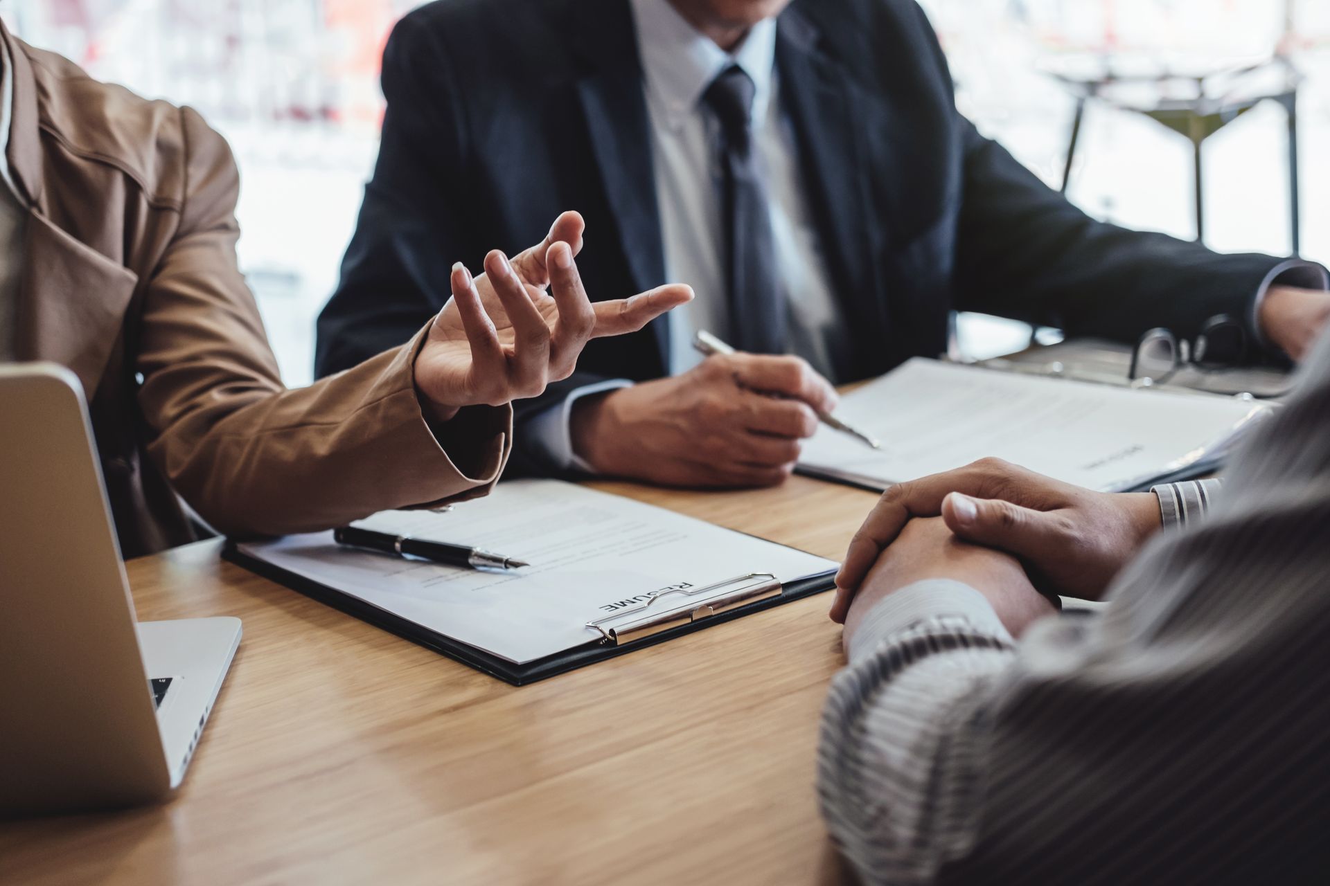 Réunion d'affaires avec trois personnes discutant de documents autour d'une table de conférence.