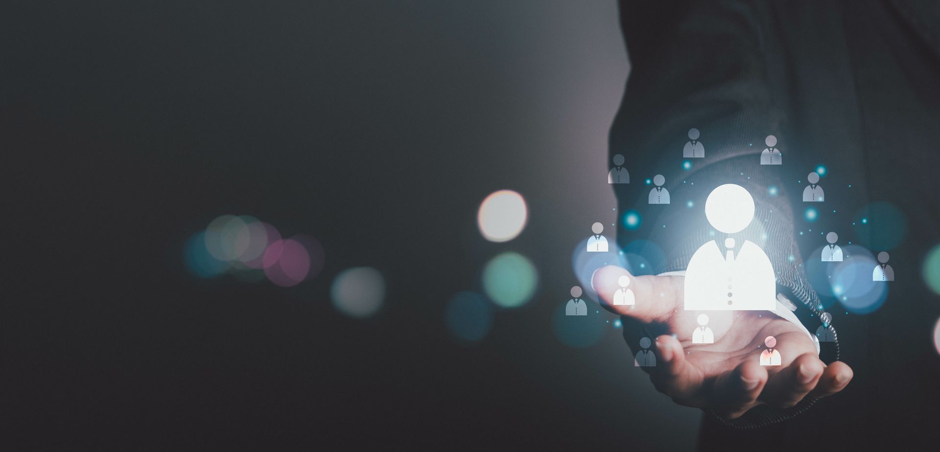 Une personne tient une icône numérique lumineuse représentant une personne, avec des symboles de réseau connectés, sur fond sombre.