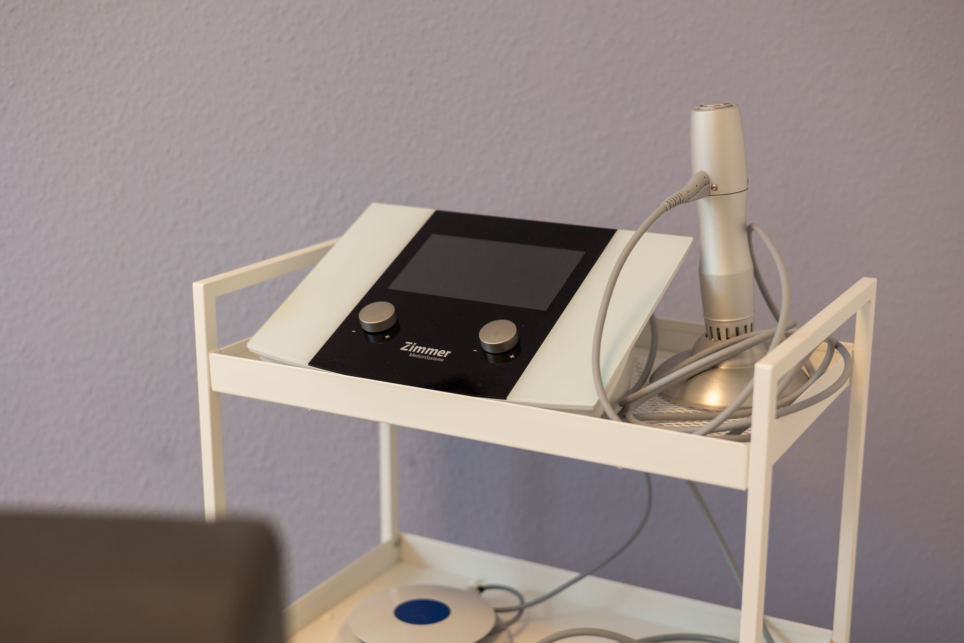 Auf einem weißen Wagen steht ein medizinisches Gerät.