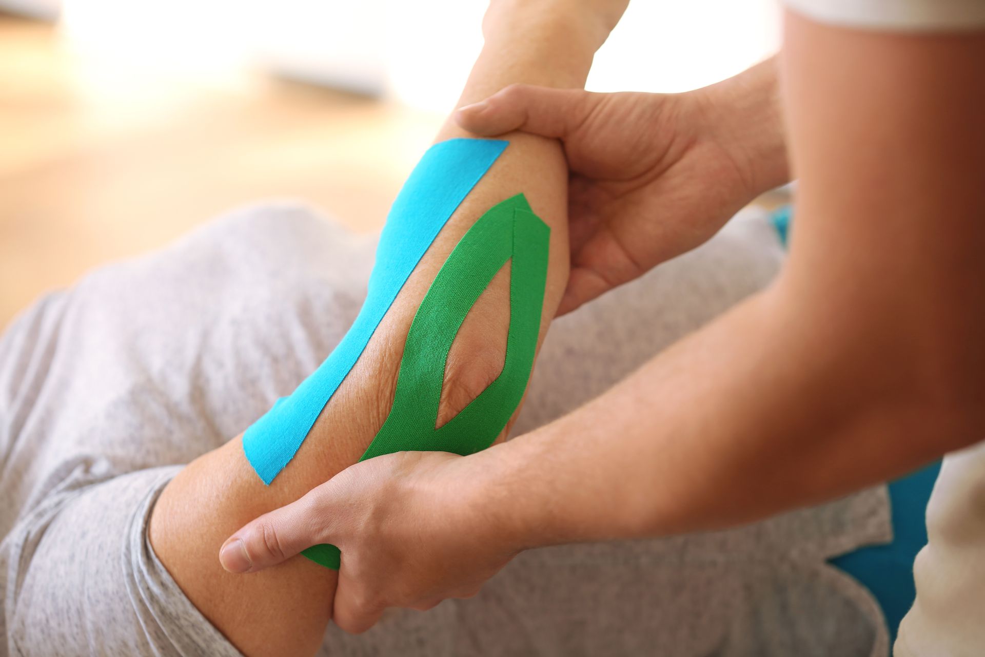 Eine Person bekommt eine Massage mit Kinesio-Tape am Knöchel.