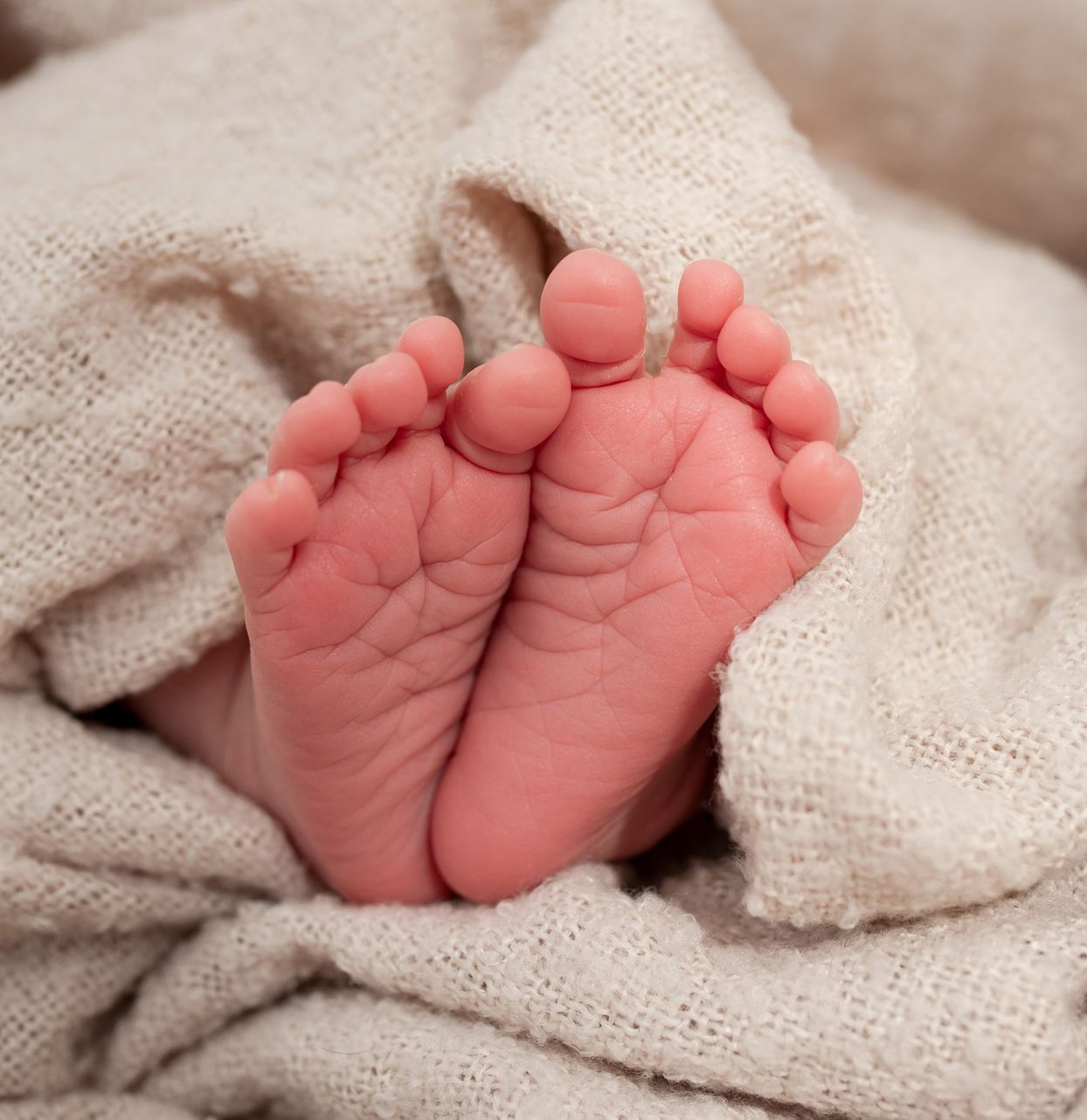 Eine Frau kniet auf einer Yogamatte und hält ein Baby in der Luft.