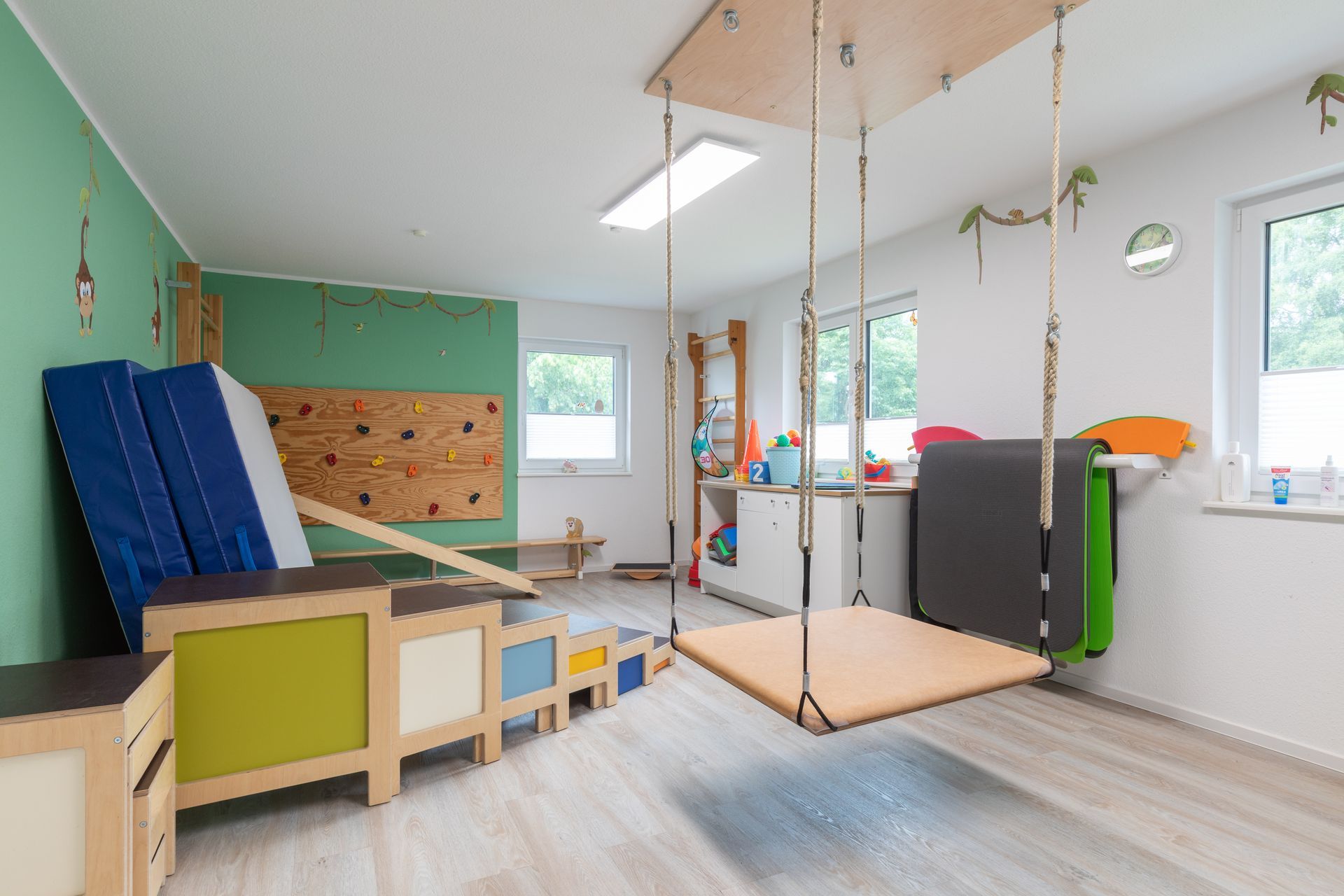 Ein Raum mit einer von der Decke hängenden Schaukel und einer Kletterwand.