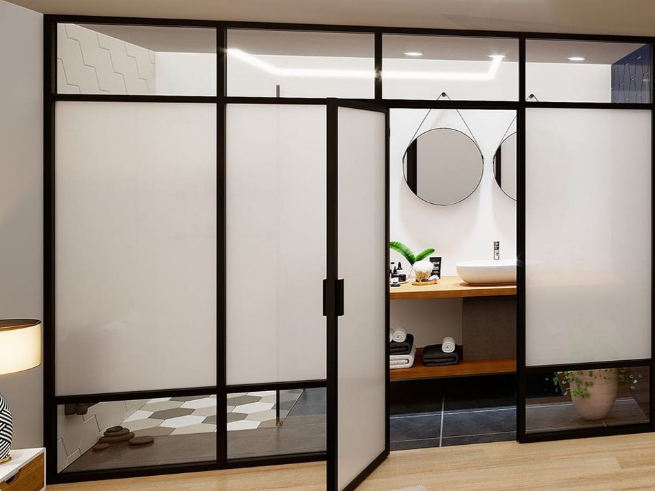 Une cloison de salle de bains avec une verrière en aluminium noir et des panneaux en verre dépoli, comportant une porte vitrée ouverte donnant sur la pièce.