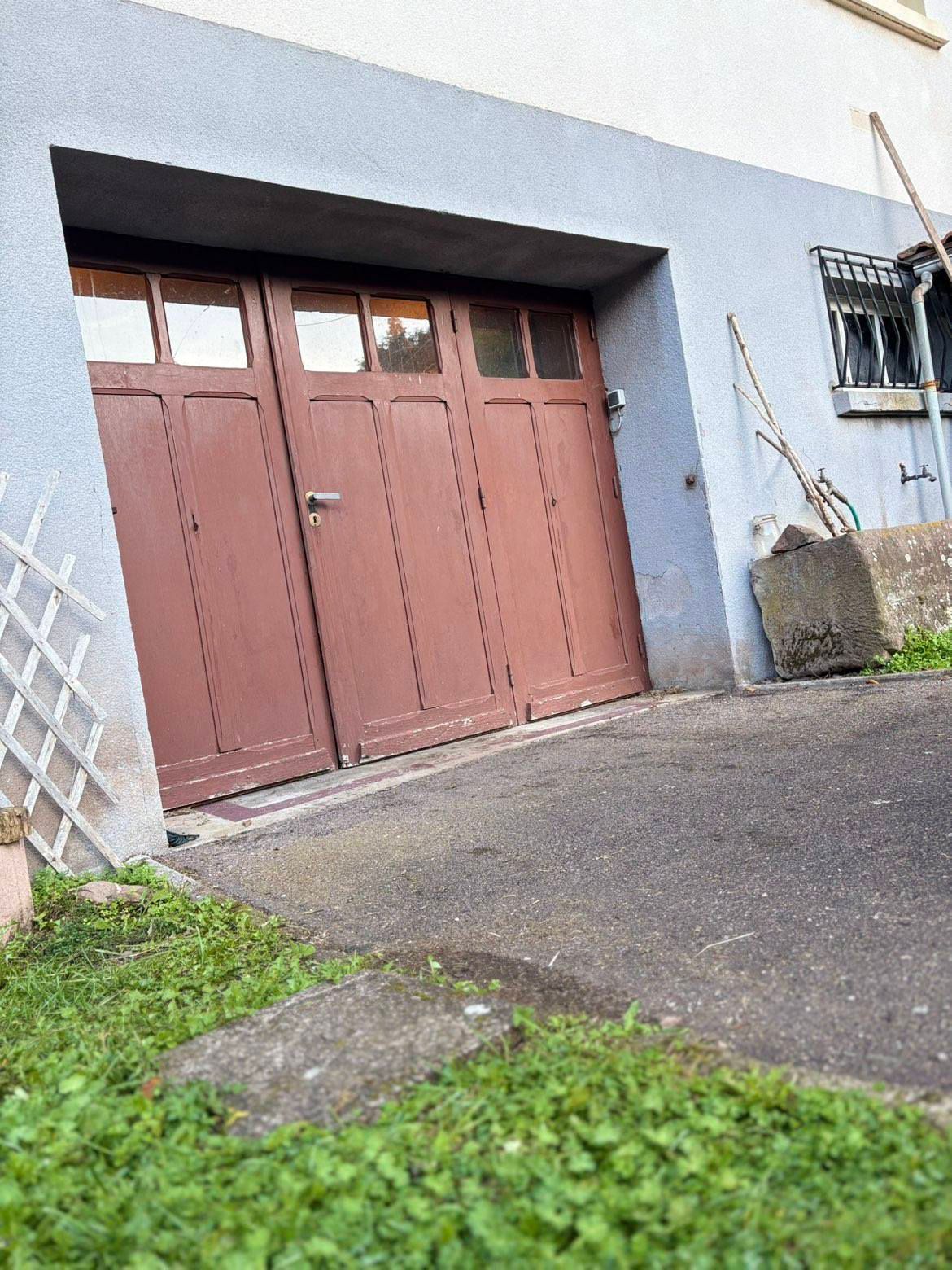 Une porte de garage ancienne en bois de couleur rouge.