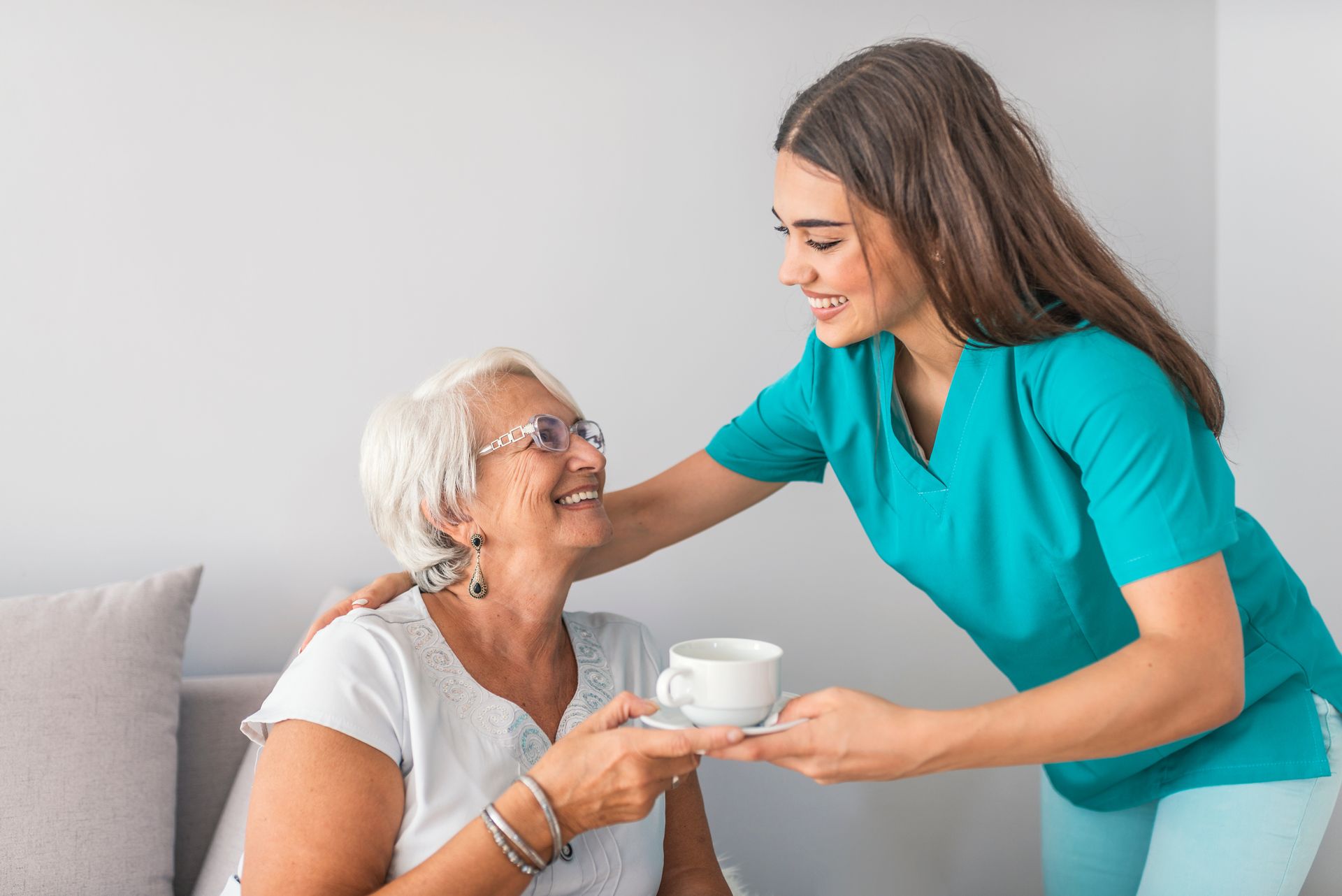 Une femme tend une tasse à café à une personne âgée